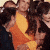 a group of people are standing around a woman in a yellow dress .