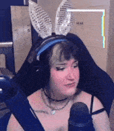 a woman wearing bunny ears sitting in front of a microphone