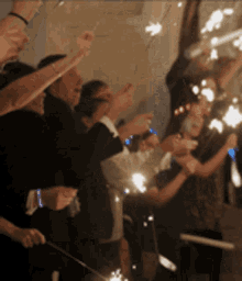 a group of people are holding sparklers up in the air