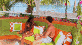 a man and a woman are sitting on a couch in front of the ocean .