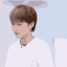 a young man with short hair is wearing a white shirt and earrings .