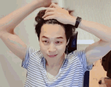 a man in a striped shirt is holding his hair