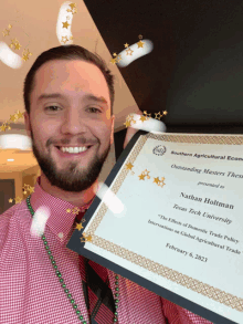 a man is holding a certificate that says nathan holtman texas tech university