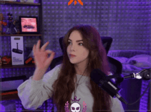 a woman is sitting in front of a shure microphone giving an okay sign .