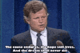 a man in a suit and tie is speaking into a microphone with the words the cause endures the hope still lives
