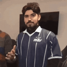 a man with a beard is wearing a blue and white striped shirt with the word mbr on the front .