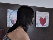 a woman stands in front of two paintings of hearts on the wall