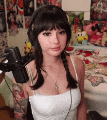a woman wearing headphones is standing in front of a microphone in a room .