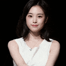 a woman wearing a white top and a necklace with a crown on it
