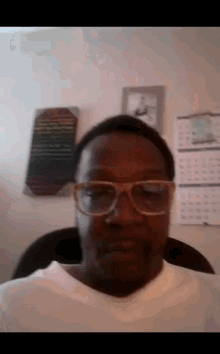 a man wearing glasses and a white shirt is sitting in a chair