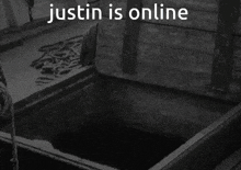 a black and white photo of a man in a hole with the words justin is online
