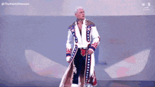 a wrestler in a red white and blue coat is standing on a stage