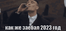 a man in a suit and tie is smoking a cigarette with the words " как же заебал 2023 год " above him