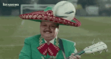 a man wearing a sombrero and holding a guitar on a field