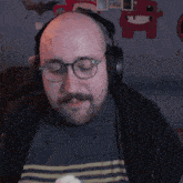 a bald man wearing headphones and glasses looks at something
