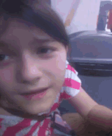 a close up of a girl 's face with a striped shirt on