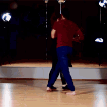 a man in a red shirt dancing with a woman in blue pants