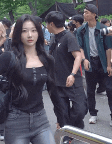 a woman in a black shirt with the letter v on it stands in a crowd of people