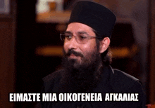 a man with a beard wearing glasses and a hat is smiling with the words eimaste mia oikogeneia agkailias below him