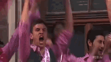 a man in a pink shirt is holding a trophy over his head