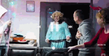 a woman in a blue robe is holding a whip in front of a man and a woman
