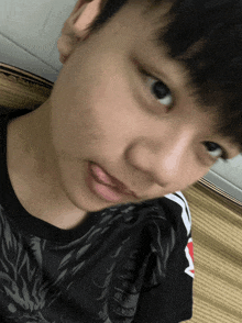 a close up of a person 's face with a black shirt with a dragon on it