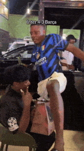 a man wearing a shirt that says inter 4-3 barça is kneeling down next to another man