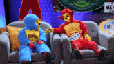 two mascots are sitting on a couch and one of them has a belt that says cmld