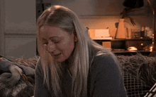 a woman is sitting on a couch with tears running down her face