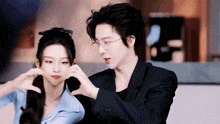 a man and a woman making a heart shape with their hands