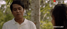 a man in a white shirt is talking to a woman in a video that says " terbaik kali langit "
