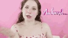 a woman in a pink dress is making a funny face and looking at the camera .