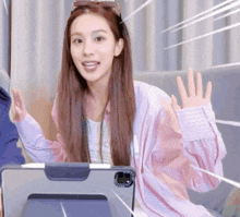 a woman in a pink jacket is sitting in front of a ipad