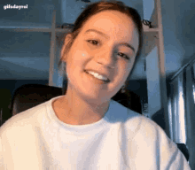 a young woman in a white sweater is smiling and looking at the camera .