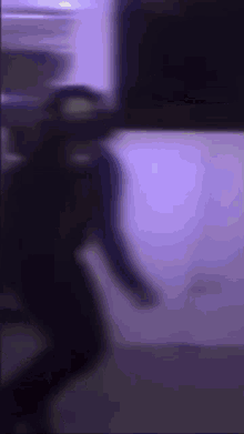 a blurry picture of a person standing in front of a purple light .