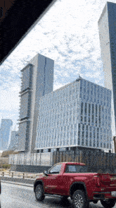 a red gmc truck is driving down a street in front of tall buildings