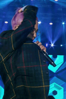 a man with pink hair is singing into a microphone