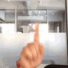 a person giving the middle finger in front of a glass window