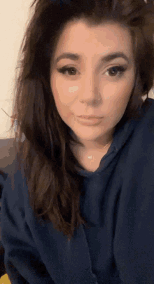 a woman wearing a blue hoodie has a nose ring