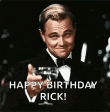 a man in a tuxedo is holding a champagne glass and toasting .
