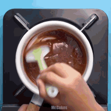 a person is stirring a pot of chocolate sauce with a spatula and the words mr.cakes on the bottom right