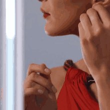 a woman in a red dress is looking at herself in a mirror