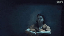 a close up of a woman 's face in a dark room with genv written on the bottom