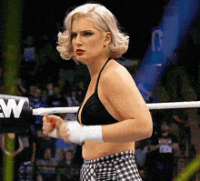 a woman in a bikini is standing in a boxing ring with the letter w on the corner