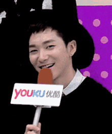 a young man is holding a microphone with a youku logo on it