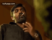 a man with a beard is smoking a cigarette with his hand .