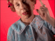 an elderly woman in a blue shirt is pointing her finger at the camera