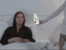 a woman in bed holds up a bottle of milk