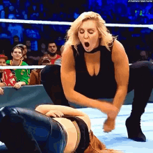 a woman is kneeling down in a wrestling ring while another woman is laying on the floor .