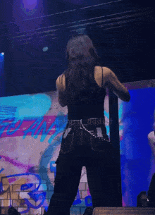 a woman in a black tank top and jeans is dancing on a stage